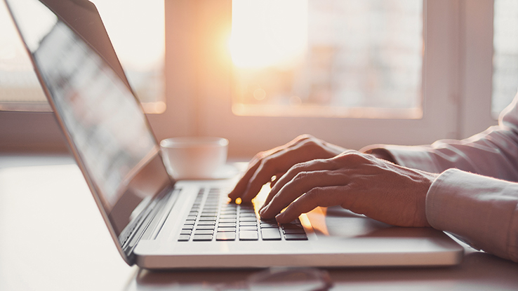 Hands typing on the keyboard of a laptop