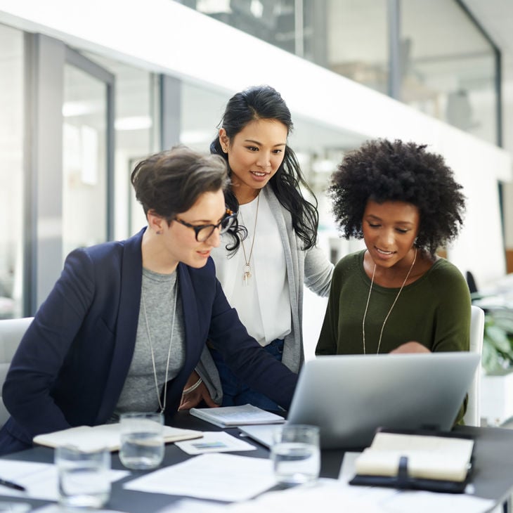 Group Of Colleagues Engaged In Discussion Around Laptop 