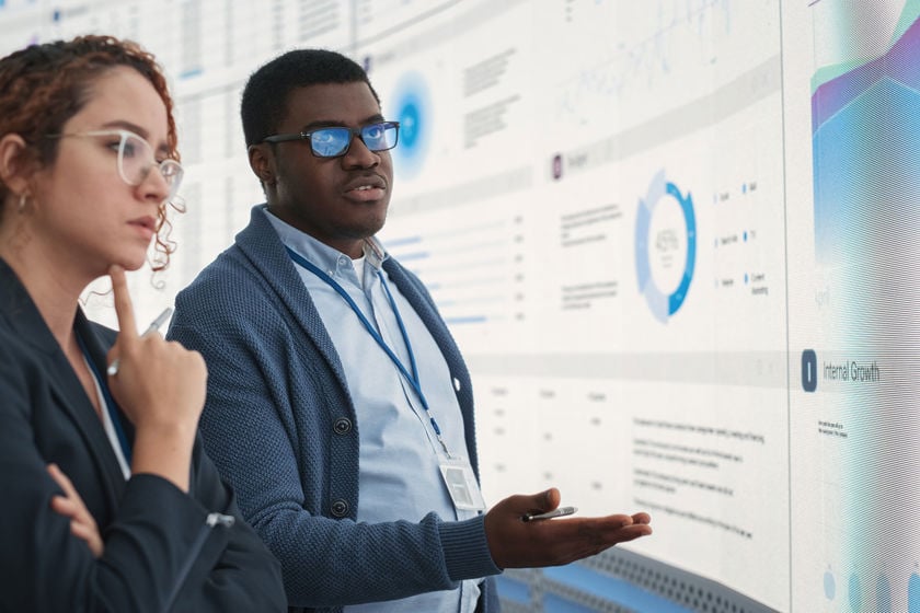 Colleagues Reviewing Data On Large Screens 