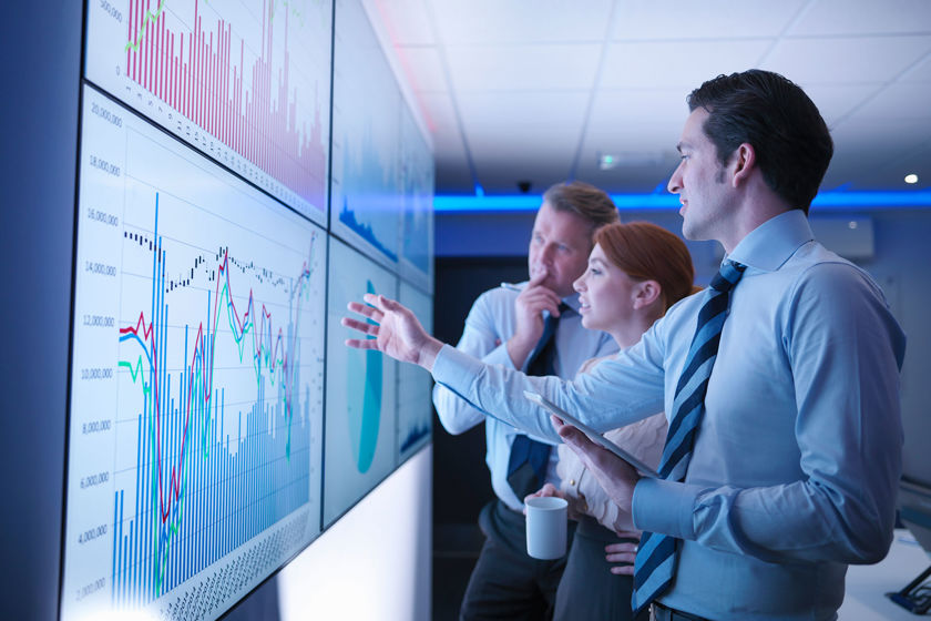 Group Of Colleagues Reviewing Data On Screens 