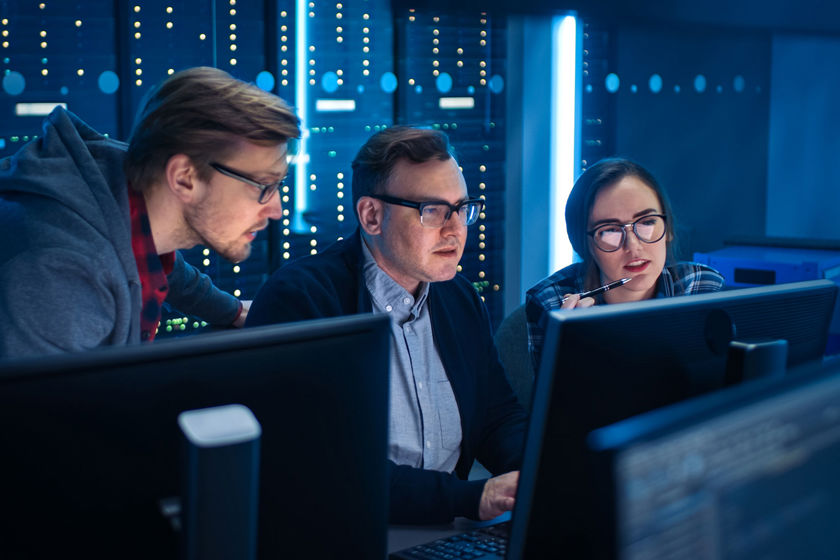 Colleagues Working At Computers In Server Room 