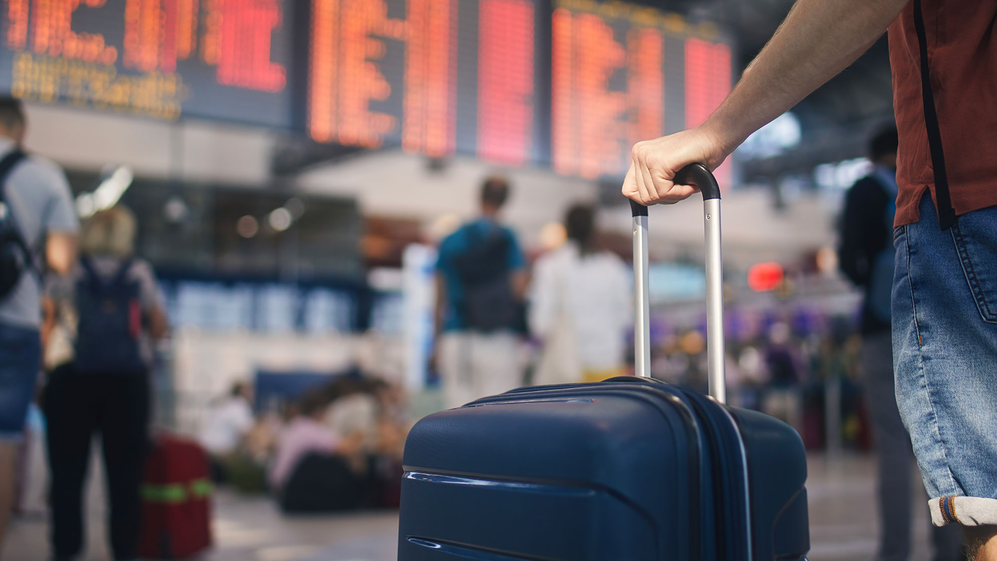 hand-holding-suitcase-in-airport-terminal