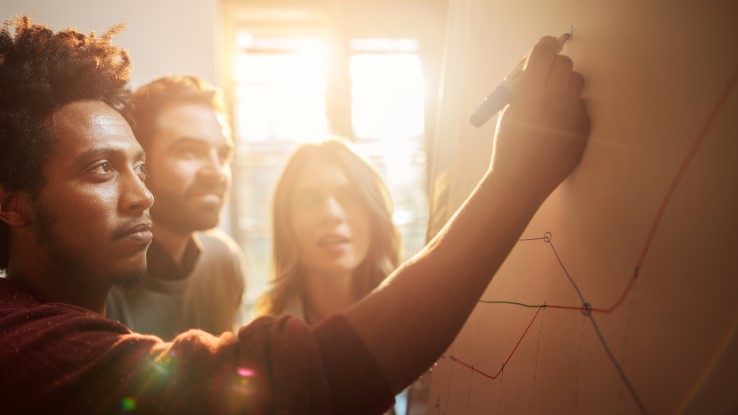 Coworkers Whiteboarding In Meeting Room 