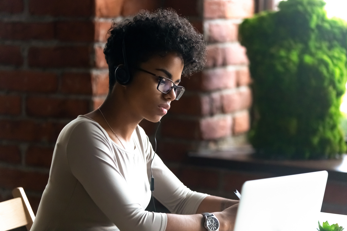 woman looking at laptop with headphones