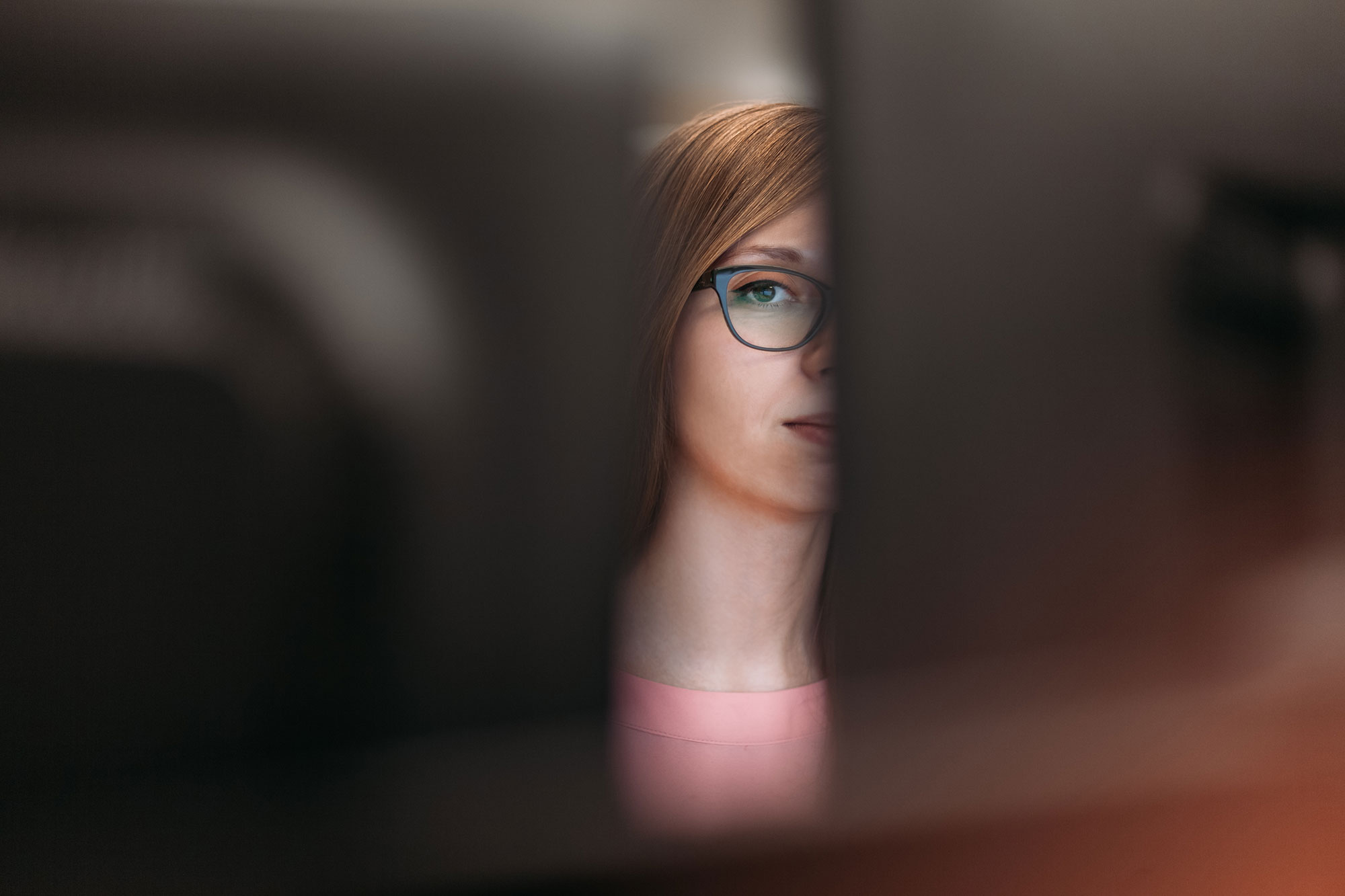 woman-peering-between-two-computer-monitors