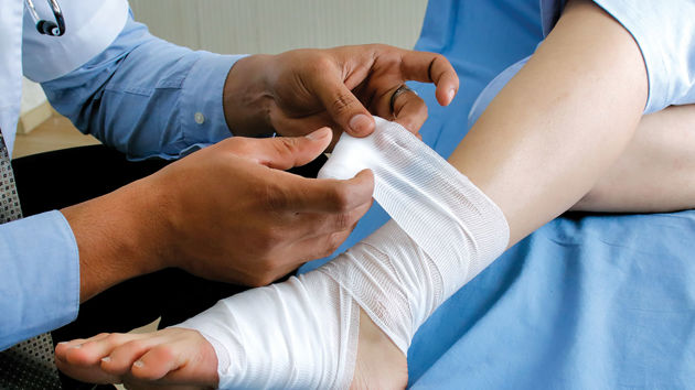 Doctor Wrapping Gauze Around Patient Ankle 
