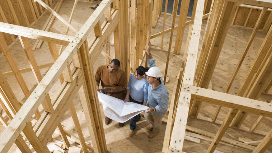 builder-and-homeowner-reviewing-blueprints-in-framed-home