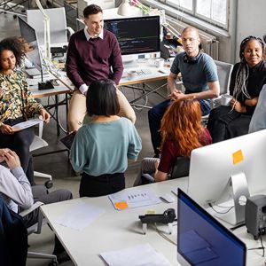Group Of Coworkers Meeting Between Desks 