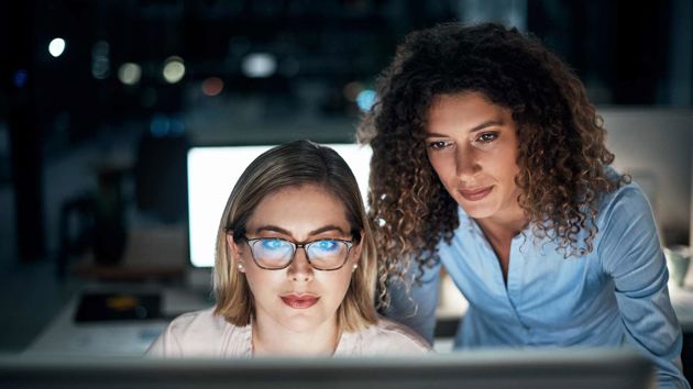 Two Colleagues Looking Intently At Data On Screen 