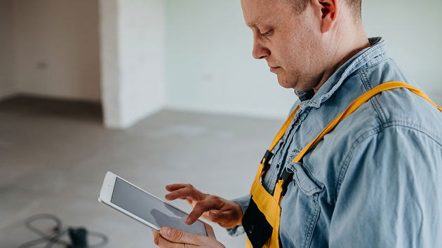 Contractor Working In Damaged Home On Tablet 