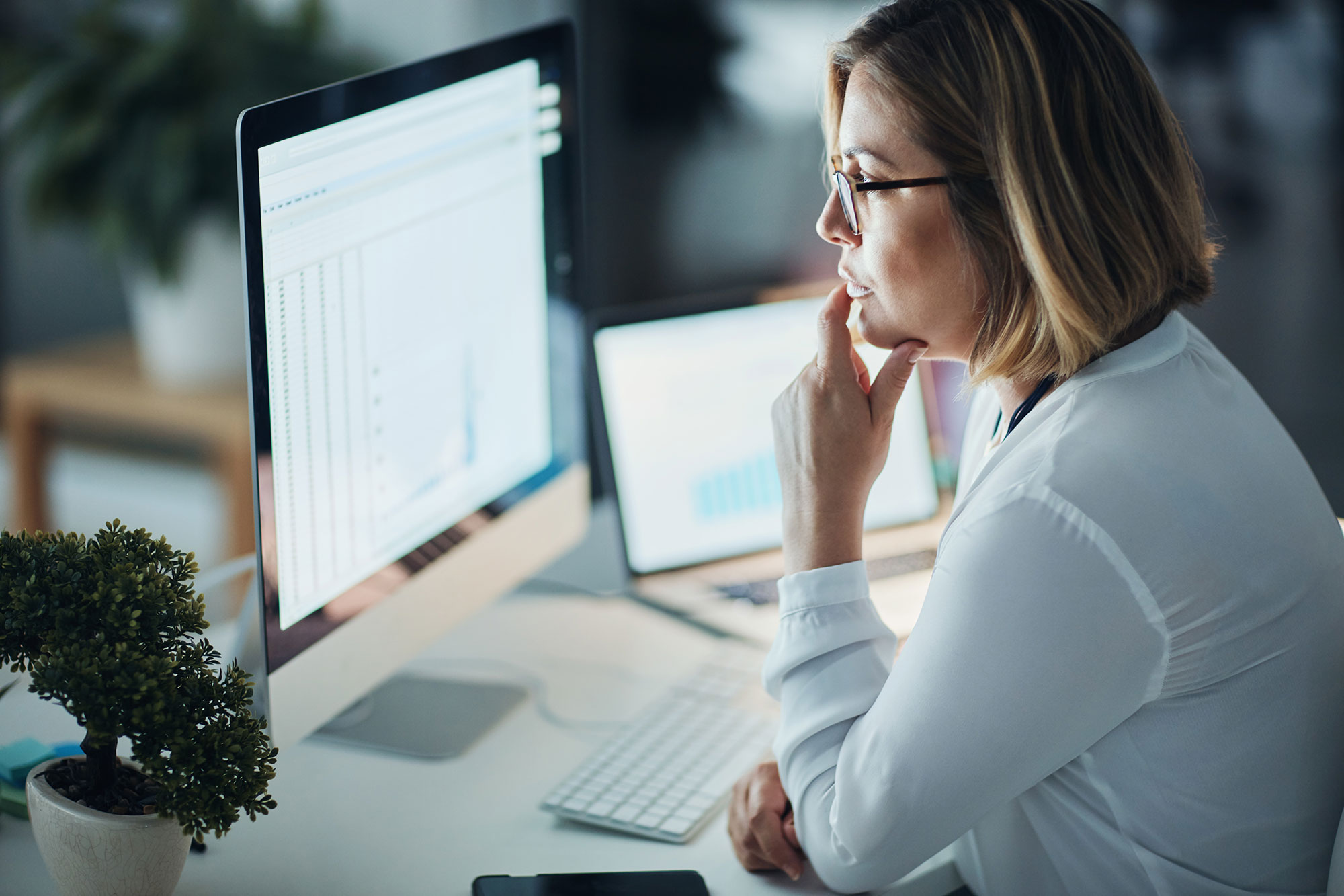 Woman Reviewing Data On Desktop Computer 