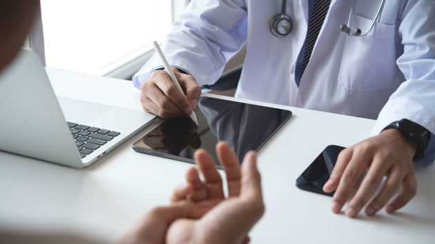 Medical Professional Recording Patient Information On Tablet 