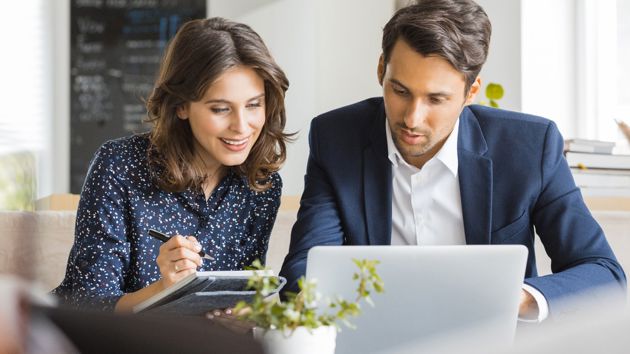Man And Woman Reviewing Information On Laptop 