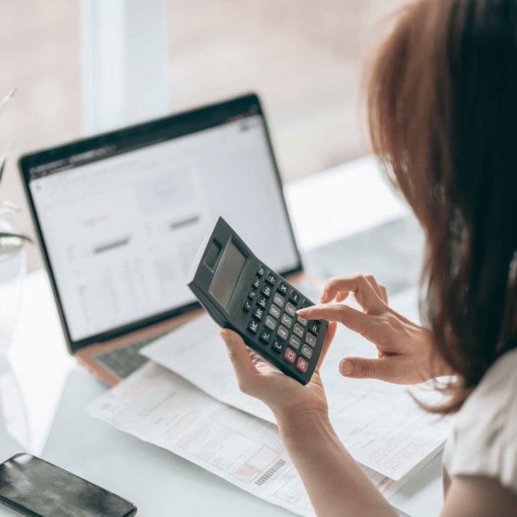 Woman Using Calculator With Paperwork 