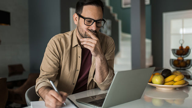 Man In Kitchen Reviewing Data On Laptop 