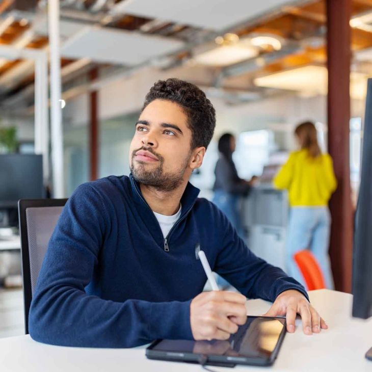 Man Writing On Tablet Looking Up To The Left 