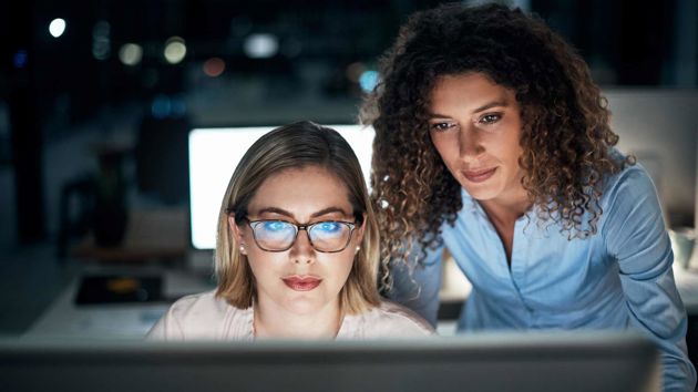 Two Colleagues Looking Intently At Data On Screen 